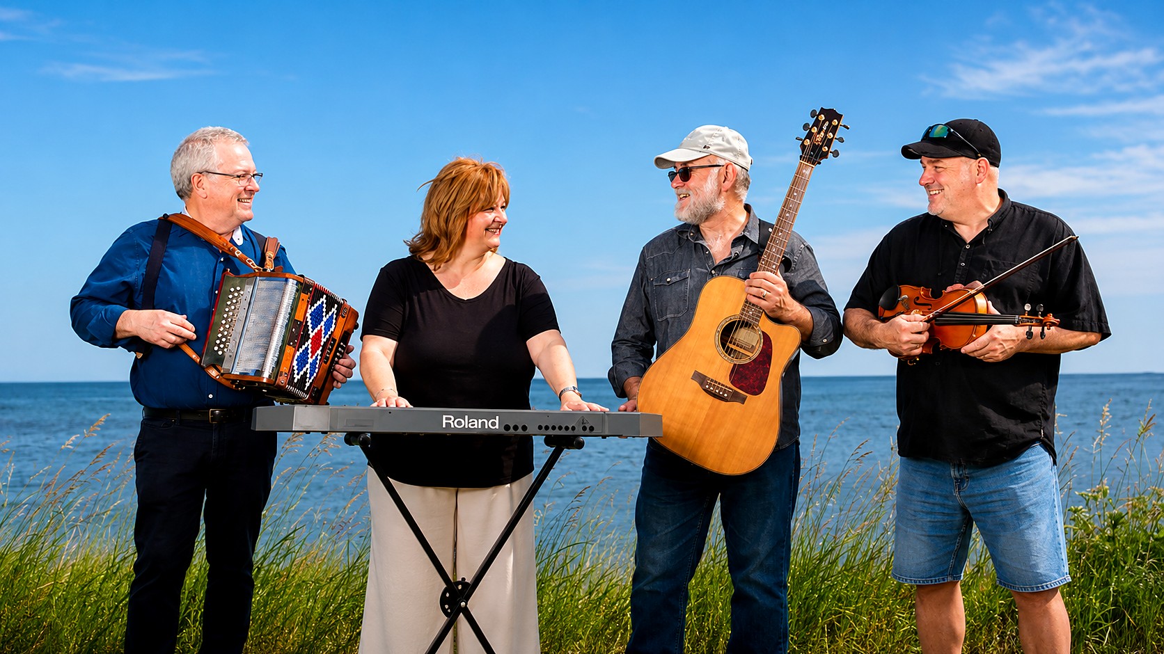 Les quatre membres de Trad'Acadie au bord de la mer avec accordéon, clavier, guitare et violon